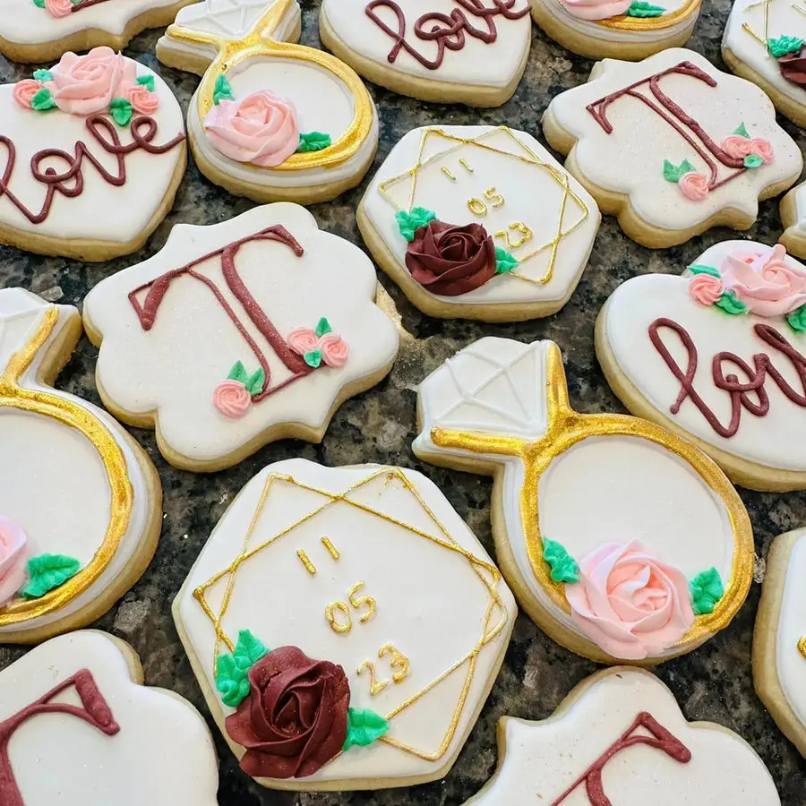 Decorated wedding-themed sugar cookies with gold rings and roses