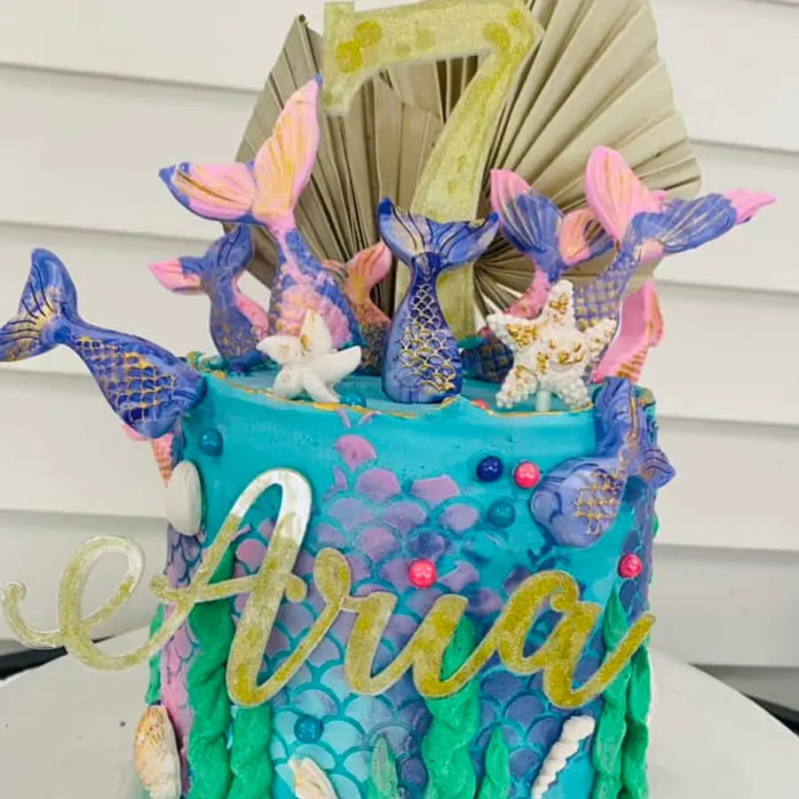 Mermaid ocean-themed birthday cake with mermaid tails and starfish